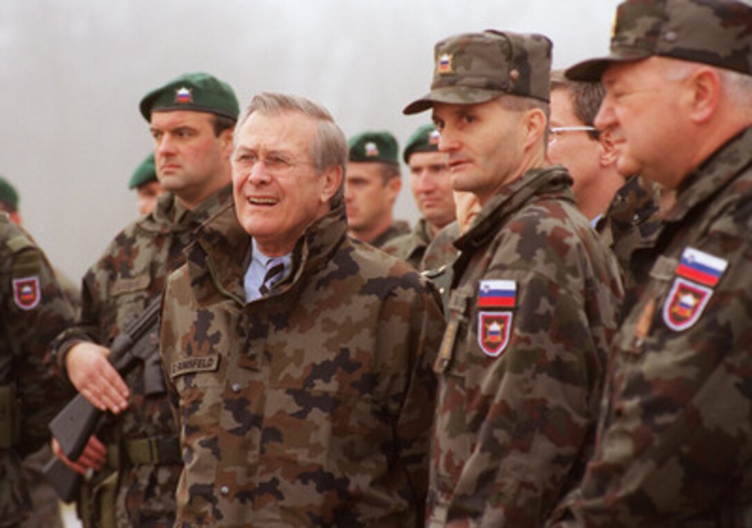 Secretary of Defense Donald H. Rumsfeld (left) talks with Capt. Bostjani Pas (center) and Brigadier Lipic, chief of the Slovenian General Staff, as he watches troops of the Slovenian Army's 1st Brigade, 10th Motorized Battalion during his visit to Ljubljana, Slovenia, on Nov. 23, 2002. This unit will soon deploy to the U.S. sector in Bosnia as part of the multinational peacekeeping force. That movement will mark the first foreign deployment of Slovenian troops. Pas will command the troops on deployment. Rumsfeld flew to Slovenia just one day after the conclusion of the NATO Summit, held in Prague, Czech Republic. At that historic meeting Slovenia and six other nations were nominated for NATO membership. 