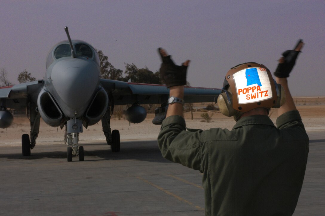 Sgt. Wayne A. Switzer, EA-6B plane captain and native of Clinton, Miss., directs a Prowler down the tarmac on its way to the flightline.