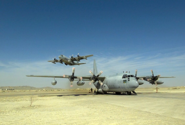 A U.S. Marine KC-130 Hercules assigned to the Raiders of Aerial Refueler-Transport Squadron Three Five Two (VMGR-352), prepares for its next mission at an undisclosed forward operating base, while a another aircraft assigned to VMGR-252 takes off on a mission to transport Marines from the 26th Marine Expeditionary Unit (MEU) back to Kandahar Airport, Afghanistan.  Marines from the 26th MEU are embarked aboard the amphibious assault ship USS Bataan (LHD 5).