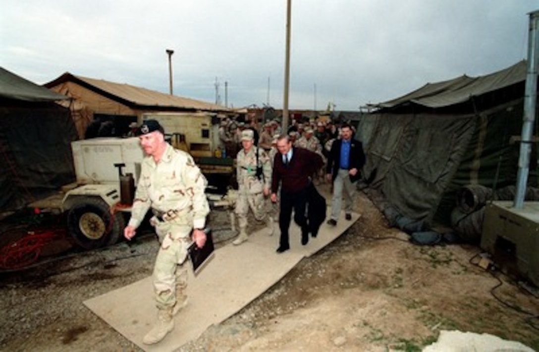 Army Col. John Mulholland, commander, 5th Special Forces Group, leads Secretary of Defense Donald H. Rumsfeld and his official party to meet with soldiers of the 10th Mountain Division and U.S. Air Force personnel on Dec. 16, 2001. The troops are deployed to central Asia for Operation Enduring Freedom. 