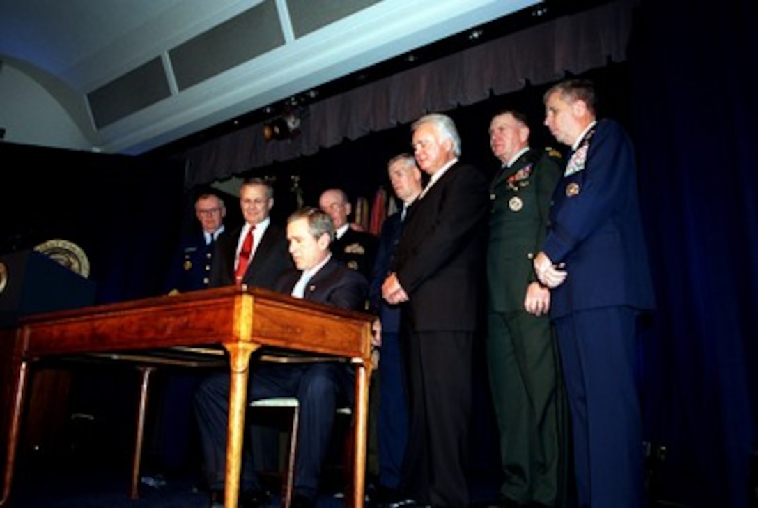 Secretary of Defense Donald H. Rumsfeld (left), Congressman C.W. Young (R-Fla.), Chairman, House Appropriations Committee and members of the Joint Chiefs of Staff watch President George W. Bush (center) as he signs the Defense Appropriations Bill at the Pentagon on Jan. 10, 2002. 