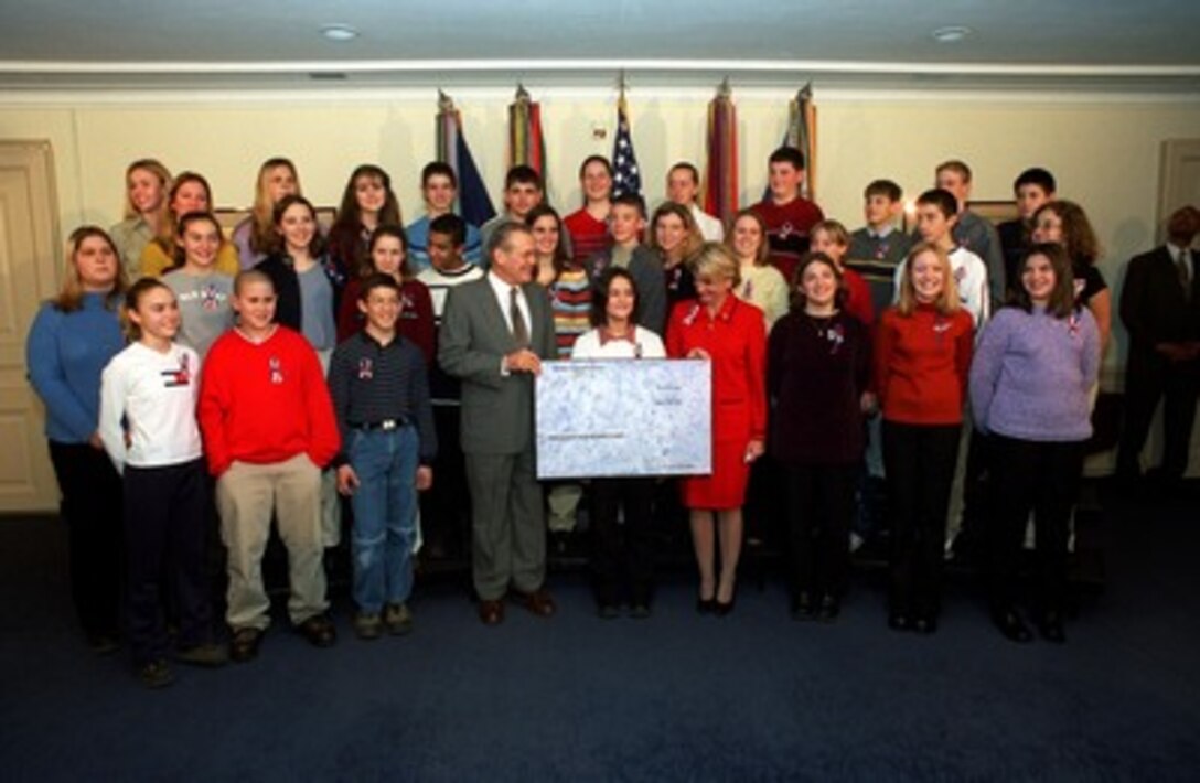 Secretary of Defense Donald H. Rumsfeld accepts a check for $10,187.93 for rebuilding the Pentagon from the 8th grade class of Moorefield Middle School, Moorefield, W. Va., during a Pentagon ceremony on Jan. 15, 2002. Lasidi Helmick (behind check) formulated the idea for the contributions during her 8th grade history class. Rep. Shelley Moore Capito (right of the check), R-W. Va., attached the plan as an amendment to the National Defense Authorization Act for Fiscal Year 2002. The plan authorizes the Secretary of Defense to accept contributions from individuals for the sole purpose of assisting in the repair of the damage caused to the Pentagon by the terrorist attack that occurred on Sept. 11, 2001. 