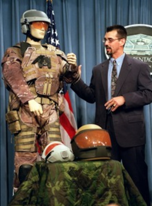 Dutch DeGay, a project engineer for the Objective Force Warrior program, briefs reporters on the Army's prototype combat uniform in the Pentagon on May 23, 2002. The helmet incorporates infrared thermal, day/night video cameras, chem-bio sensors, a global positioning system, broadcast heads-up display and ballistic protection. The torso garment incorporates body armor and has physiological status monitors that allows the individual soldier, as well as the medics on the battlefield, to know exactly what the individual soldier's physical condition is at any given time. The uniform is suitable for all climate conditions, having the capability of being heated or cooled. The combat uniform is being researched and developed at the U.S. Army's Soldier Systems Center, Natick, Mass. 