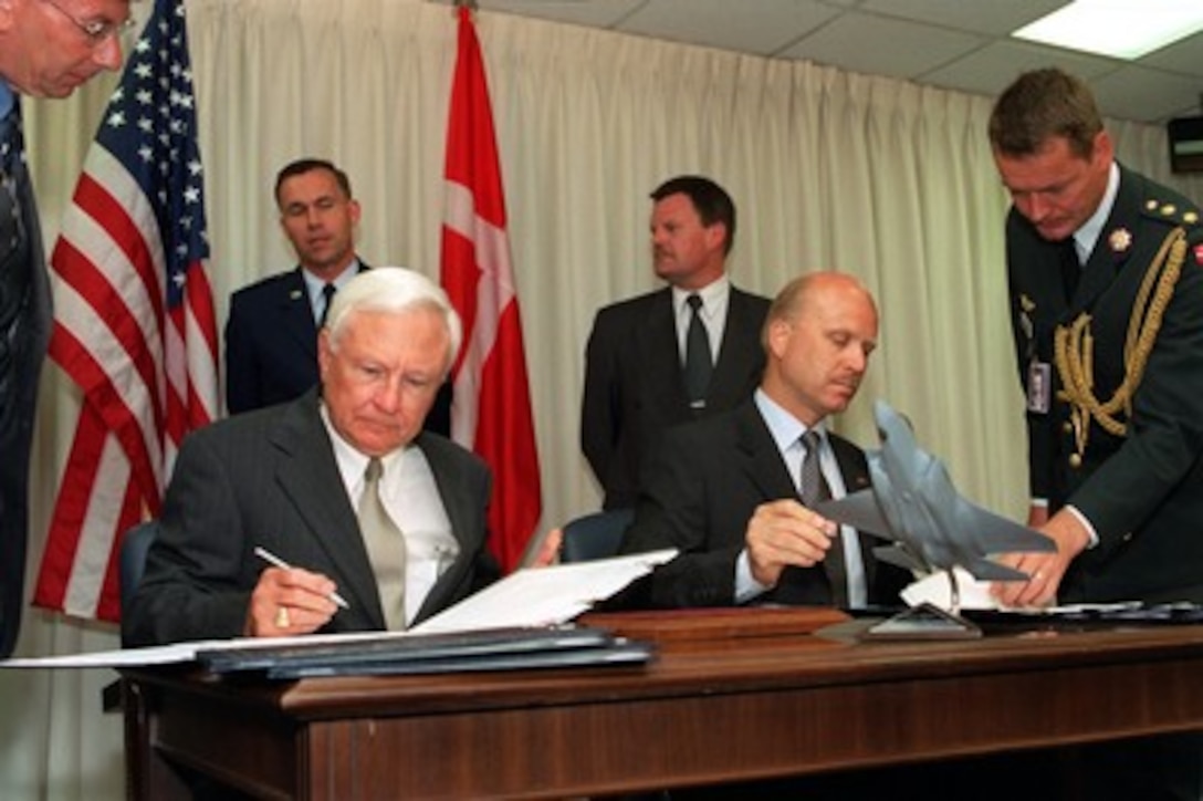 Under Secretary of Defense for Acquisition, Technology, and Logistics Edward C. "Pete" Aldridge (seated left) and his Danish counterpart, Deputy Permanent Secretary of State for Defense and National Armaments Director Jorgen Hansen-Nord (seated right), sign a memorandum of understanding in the Pentagon on May 28, 2002. The memorandum commits Denmark to participate in the joint strike fighter system development and demonstration phase. The joint strike fighter is the military's next generation, multi-role, strike aircraft designed to complement the Navy F/A-18 and the Air Force F-22 aircraft. The joint strike fighter program is the largest DoD acquisition program in history. 