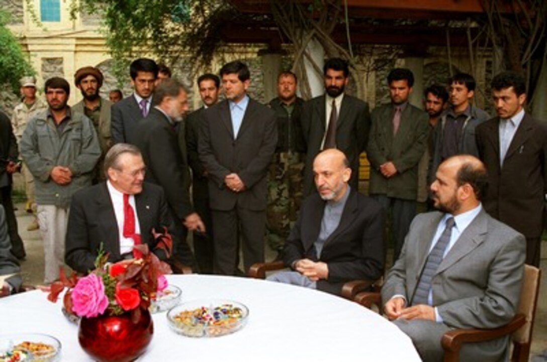 Secretary of Defense Donald H. Rumsfeld (seated left) meets with Afghan Interim Authority Chairman Hamid Karzai (center) in the courtyard of the Presidential Palace in Kabul, Afghanistan, on April 27, 2002. Rumsfeld and Karzai are discussing how to provide for the security of the fledgling new democratic government. Mohammad Fahim (right), the Afghan Interim Authority defense minister, joined in the discussions. 