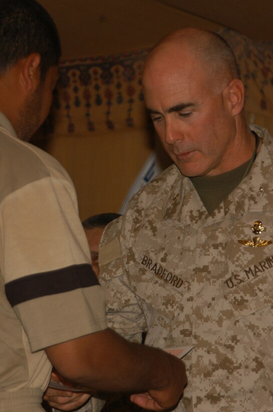 AL ASAD, Iraq (April 9, 2005) - Col. Kent W. Bradford, guest of honor, gives a graduation certificate to a new graduate of the Iraqi Border Patrol School during a ceremony here April 9. The border patrolmen went through three weeks of training in advanced law enforcement tactics, techniques and procedures.