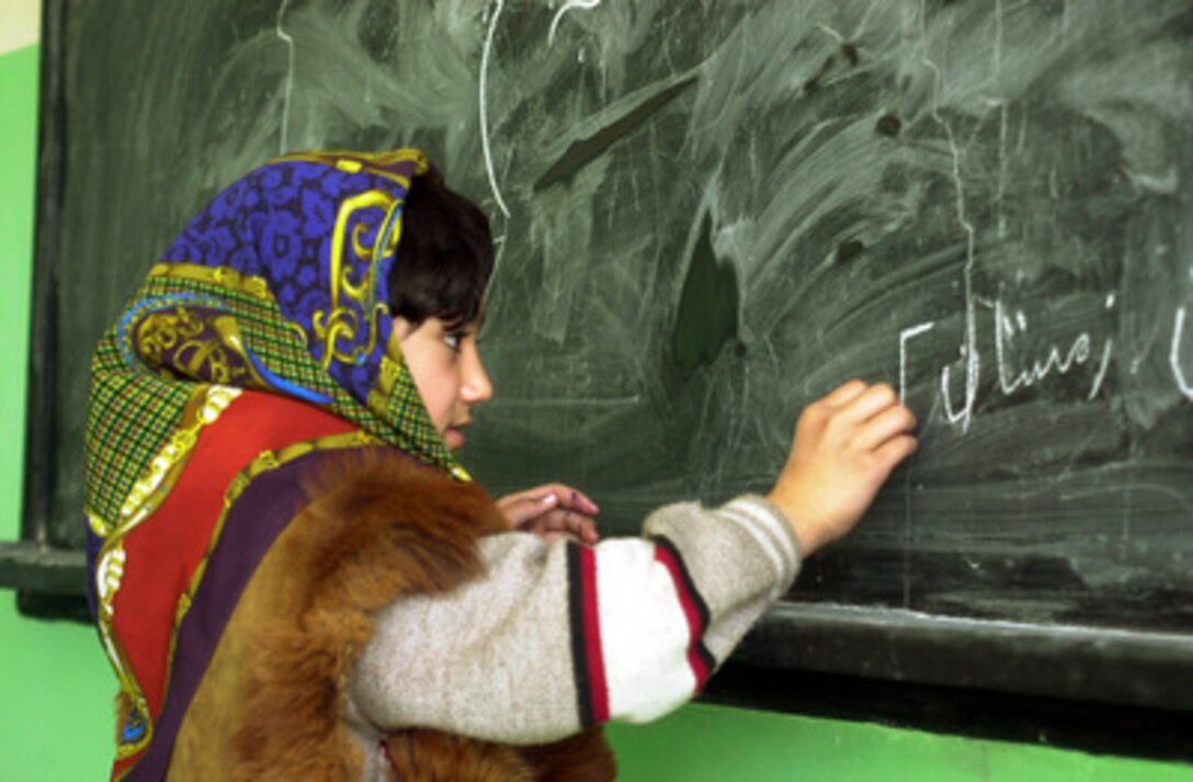 An Afghan girl writes on the blackboard during a class in the Rukhshana School on March 11, 2002. Girls are now openly attending the school that was nearly destroyed during the Afghan civil war. The Rukhshana School will become the first Coalition Joint Civil Military Operations Task Force project funded in Kabul, Afghanistan. The Freedom Construction Company, an Afghan company, was contracted to remove the war debris in preparation for rebuilding the school. 