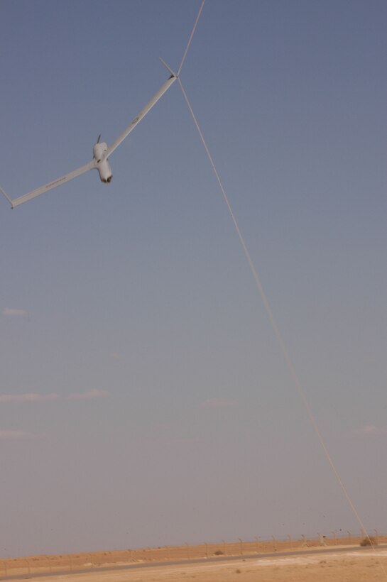 AL ASAD, Iraq--A ScanEagle UAV catches a small rope using what is called a skyhook retrieval system.  This UAV just returned from an intelligence, surveillance, and reconaissance mission over western Iraq.  The ScanEagle UAV is operated by a small detachment of Marines and civilians making up Marine Unmanned Aerial Vehicle Squadron 2, 2nd Marine Aircraft Wing, from Cherry Point, N.C.  The detachment is deployed here to provide intelligence, surveillance, and reconnaissance in western Iraq.  ScanEagle weighs approximately 40 pounds and has a 10-foot wing span.  The aircraft operates with a small engine, requiring a small amount fuel.  Its 4-foot frame can remain airborne for more than 10 hours.  Each drone is launched using a catapult system, which makes it runway independent and perfect for forward operating forces.  Using the Global Positioning System, it is retrieved with a skyhook where the UAV catches a small, suspended rope.   This detachment collects information on potential targets, so the leaders on the ground can decide what effective measures to take to minimize the risks against friendly forces.  Spending almost 15 hours a day gathering information, the analysts provide a solid foundation to make tactical decisions.
