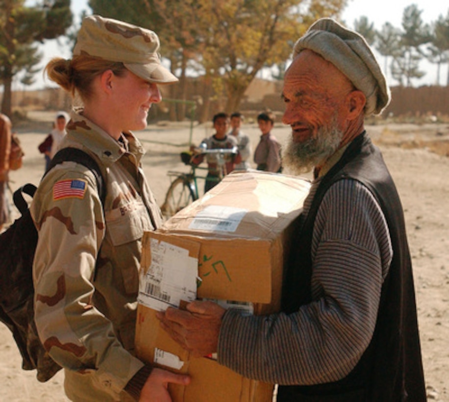 U.S. Army Spc. Jessica Briskie gives a box of clothing to an Afghan gentleman in Bagram, Afghanistan, on Oct. 30, 2002. Personnel from the 44th Task Force Combat Support Hospital at Bagram Air Base are giving clothes and school supplies to the students and staff at Bagram Air Base High School. Members of the 339th Combat Support Hospital, Pittsburgh, Pa., and the surrounding community donated hundreds of school supplies, clothing and perishables to the children of Bagram. 