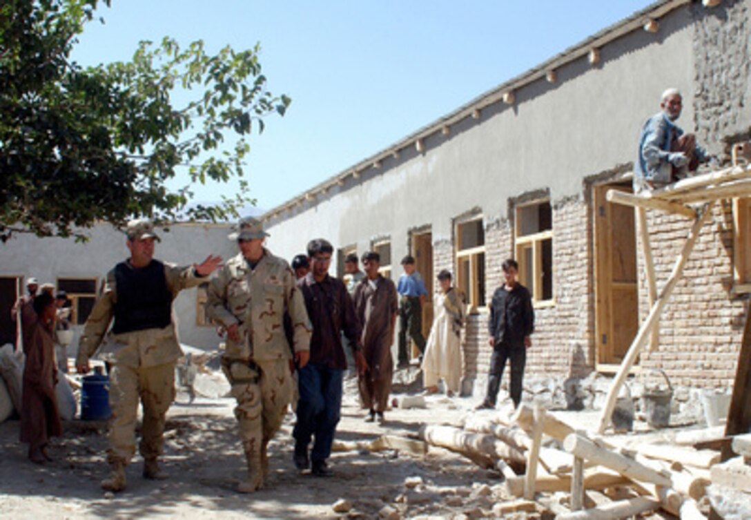 Soldiers from the 489th Civil Affairs Battalion, of Knoxville, Tenn., inspect the progress being made on the construction of a new school in the Parwan Province of Afghanistan on Sept. 8, 2002. The soldiers are members of the Coalition/ Humanitarian Liaison Cell, and are currently overseeing the construction of six schools, two bridges, a major tunnel, and two fresh water pumps in the province. 