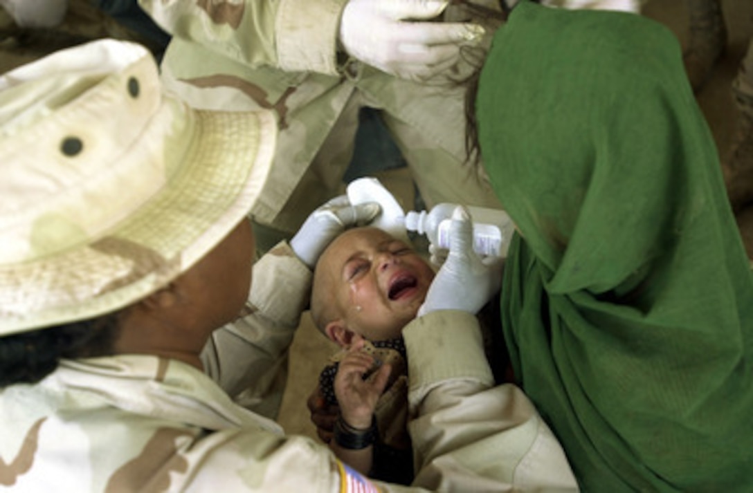 Army Staff Sgt. Betsy Pulley helps administer medical attention to an Afghan child diagnosed with pink eye in Kandahar, Afghanistan, on Oct. 6, 2002. Pulley, of the 488th Quartermaster Company, Fort Polk, La., is treating the child outside a school rebuilt by American and Canadian forces. The medical treatment and the rebuilding of the school are part of humanitarian assistance programs designed to help the people of Afghanistan. 