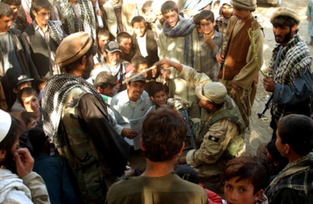 A soldier waves a stick as he teaches a crowd in Nejhab, Afghanistan, how to count in English on Oct, 26, 2002. Soldiers from the 489th Civil Affairs Battalion, Knoxville, Tenn., and the 9th and 8th Psychological Operations Battalion, Fort Bragg, N.C., are delivering a humanitarian aid package to the village of Nejhab. The soldiers brought 10 medium-size tents, 250 blankets, and three medical kits for the villagers before the cold weather begins. 