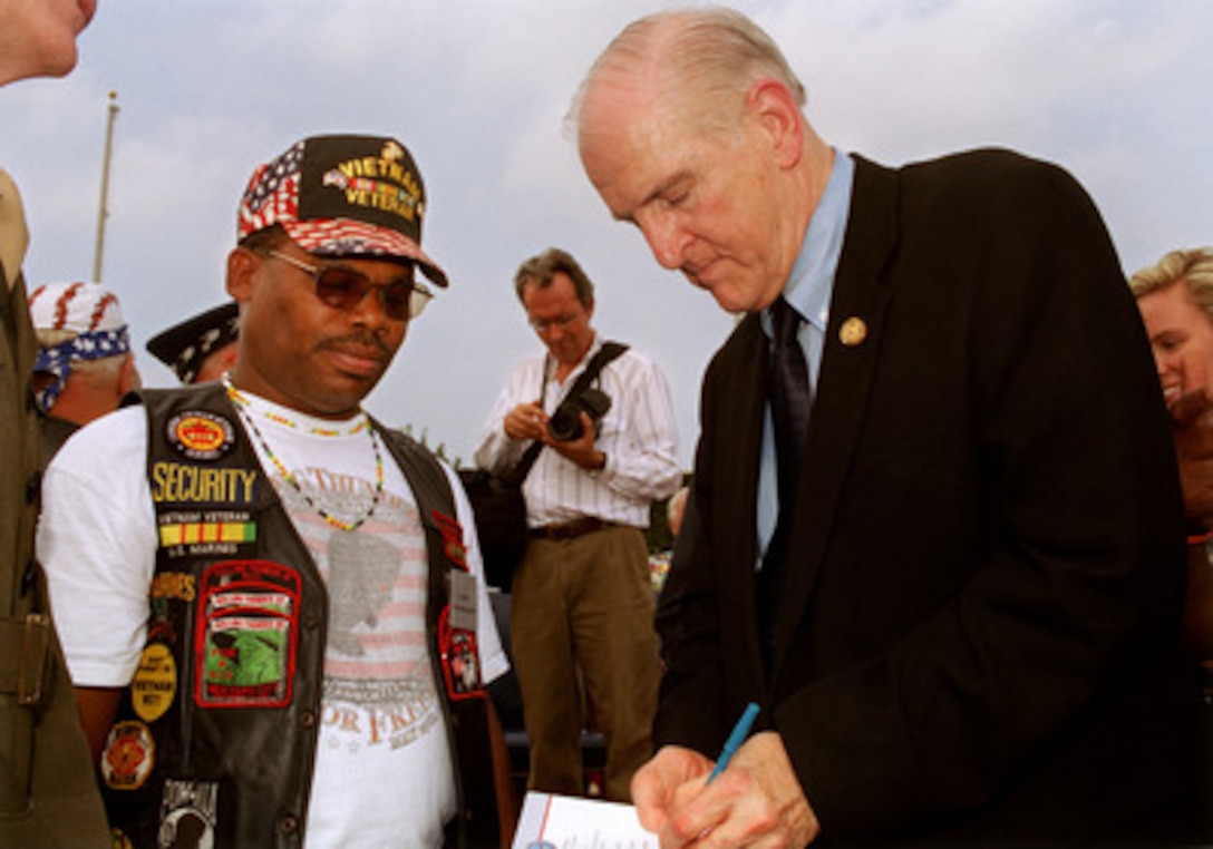 Texas Congressman Sam Johnson, keynote speaker at the National POW/MIA Recognition Day ceremony held at the Pentagon on Sept. 20, 2002, signs an autograph for a fellow Vietnam War veteran. Johnson, an Air Force fighter pilot during the Korean and Vietnam Wars, spent seven years in captivity in Hanoi, Vietnam, after his F-4 Phantom was shot down on his 25th combat mission of that war. Secretary of Defense Donald H. Rumsfeld and Chairman of the Joint Chiefs of Staff Gen. Richard B. Myers co-hosted the annual event. 