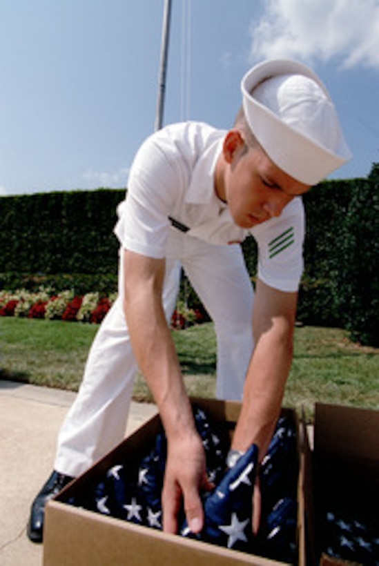 Navy Seaman Apprentice Aaron D. Burden packs a flag after raising it on a flagpole at the Pentagon on Aug. 15, 2002. These commemorative flags are to be shipped to ships and U.S. military installations around the world. 