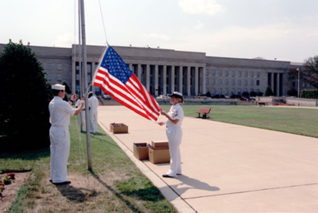 Navy Seamen Mark A. Catalano and Seaman Tiffany J. Noles prepare to raise a flag on a flagpole at the Pentagon on Aug. 15, 2002. These commemorative flags are being sent to ships and U.S. military installations around the world. 
