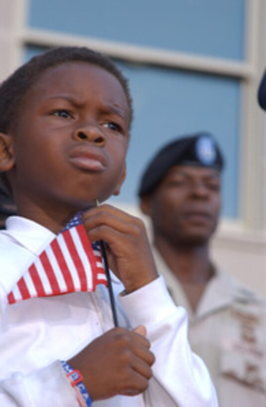 Ten year old Andre Hinton holds an American flag while U.S. Army First Sergeant Curtis O'Neal stands behind him during the Pentagon Observance Ceremony at the Pentagon Phoenix Project Site on Sept. 11, 2002. More than 13,000 people attended the service to remember those who lost their lives one year ago when terrorists crashed a commercial airliner into the Pentagon. 