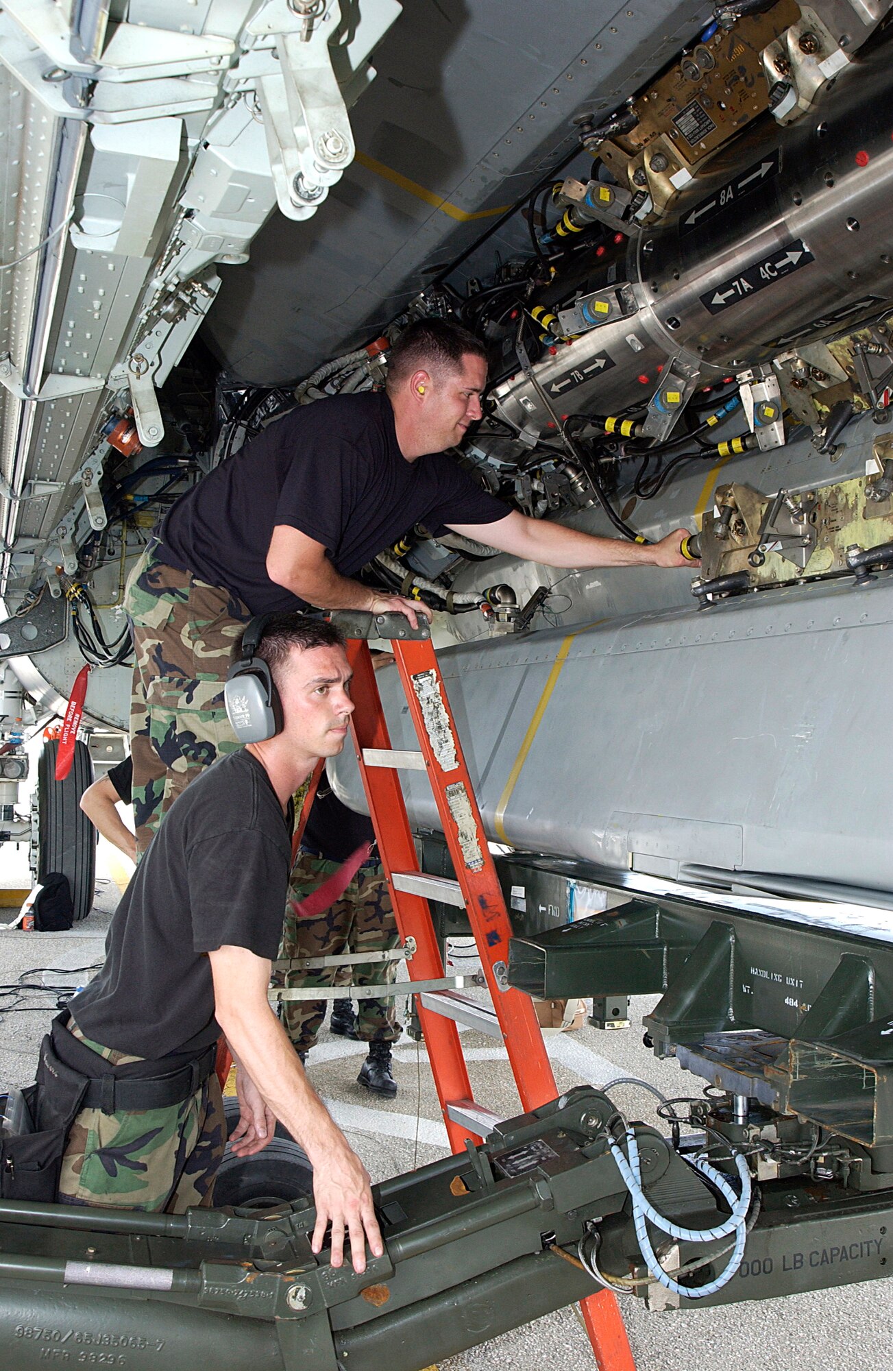 ANDERSEN AIR FORCE BASE, Guam  --  Staff Sgts. John Beldin (top) and Landon Favors, B-52 Stratofortress weapons loaders, prepare an air-launched cruise missle for loading on a B-52 here March 20.  Aircraft and support troops from the 2nd Bomb Wing at Barksdale Air Force Base, La., are deployed as part of the 7th Air Expeditionary Wing.  (U.S. Air Force photo by Senior Airman Christina M. Rumsey)