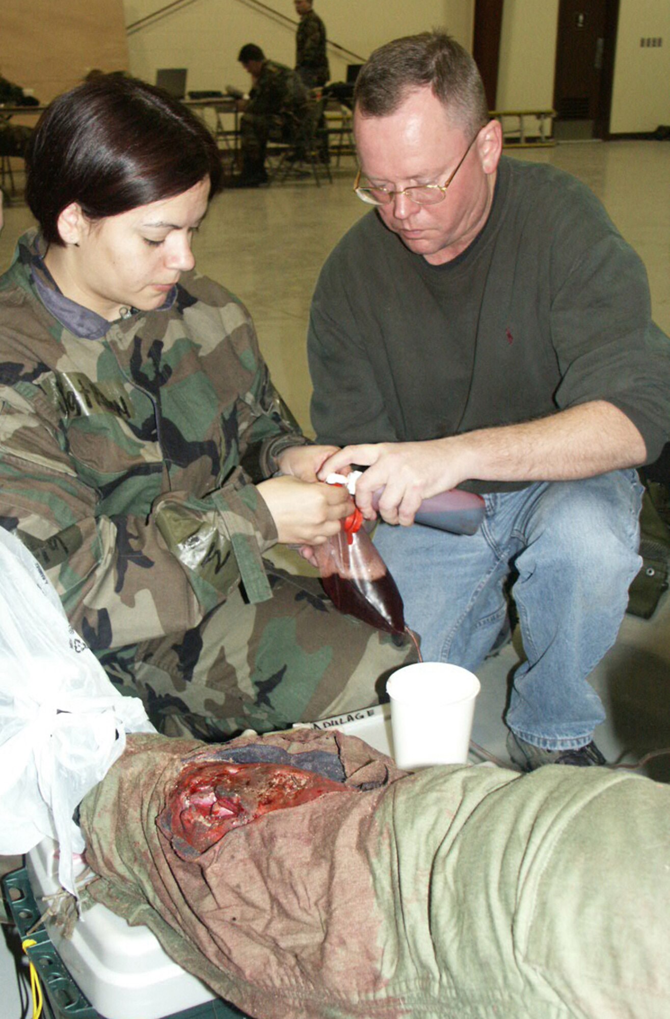 TAEGU AIR BASE, South Korea -- Staff Sgt. Sonia Rincon (left) and Capt. Ken Brown fill a bag with fake blood as they apply injuries to a simulated victim.  Both are assigned to the 353rd Operations Support Squadron medical flight at Kadena Air Base, Japan.  These fake wounds, known as moulage, add to the realism of casualty exercises.   (U.S. Air Force photo by Senior Airman Andrew Svoboda)