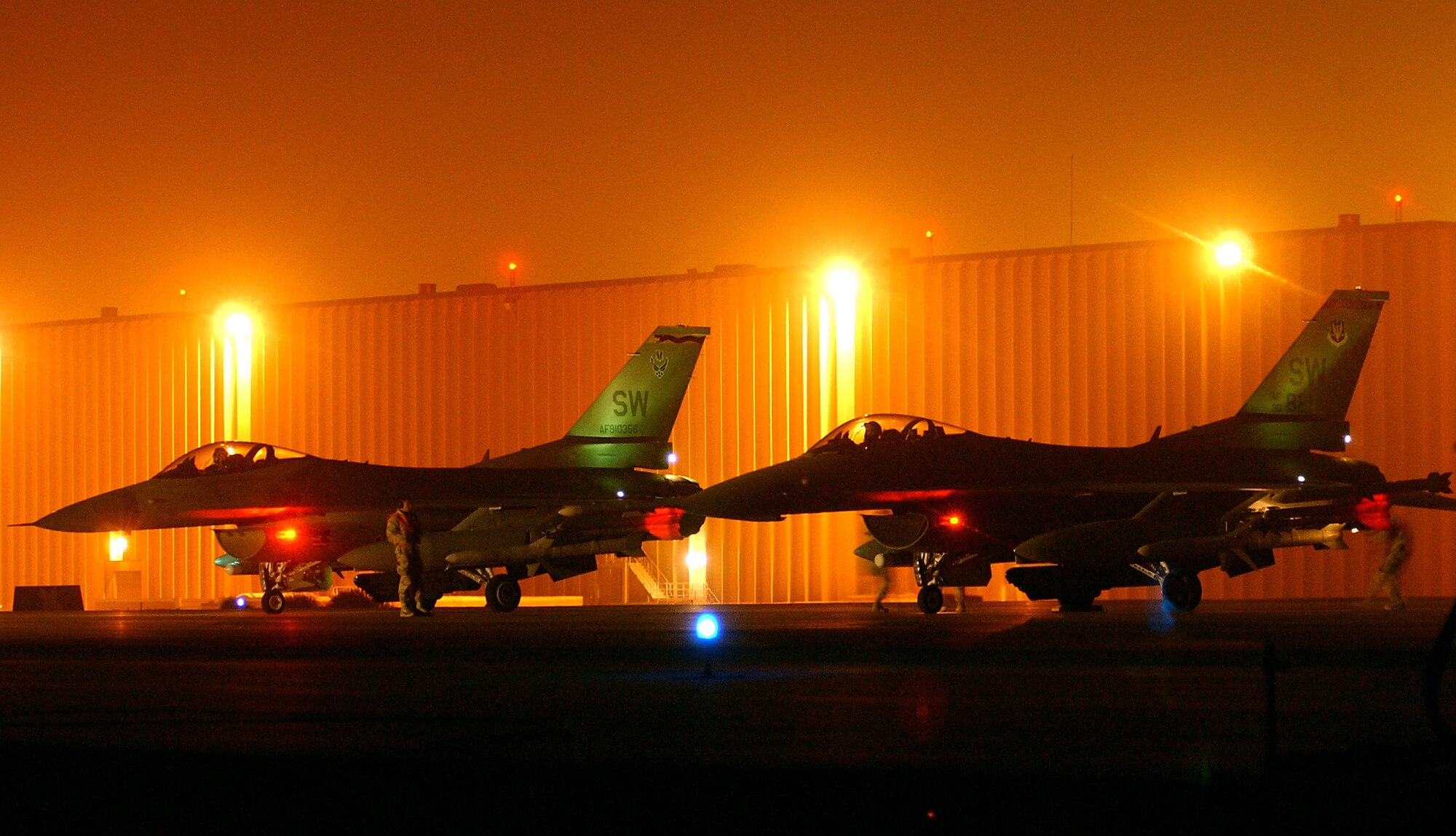 OPERATION IRAQI FREEDOM --  F-16 Fighting Falcons wait on the "hot ramp" at a forward-deployed location while maintenance crews ready the weapons for a night mission March 21.  The F-16s are from the 20th Fighter Wing at  Shaw Air Force Base, S.C., and they are flying Operation Iraqi Freedom missions for the 363rd Expeditionary Fighter Squadron. (U.S. Air Force photo by Staff Sgt. Matthew Hannen)                        