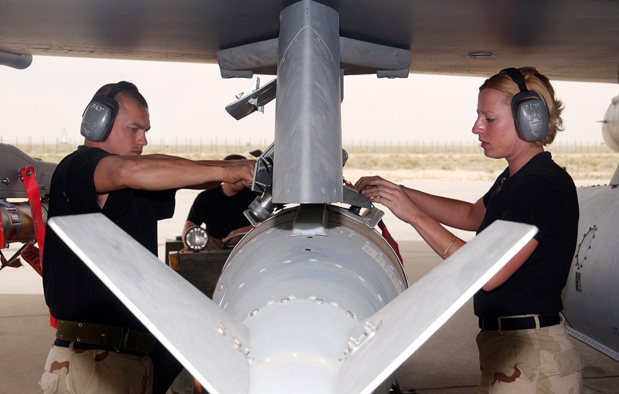 OPERATION IRAQI FREEDOM -- Staff Sgt. Mike Amado and Airman 1st Class Stacy Brenenstall load a joint direct attack munition onto an F-16 Fighting Falcon at a desert air base.  Both airmen are members of the 332nd Expeditionary Aircraft Maintenance Squadron.  (U.S. Air Force photo by Master Sgt. Stefan Alford)
                   