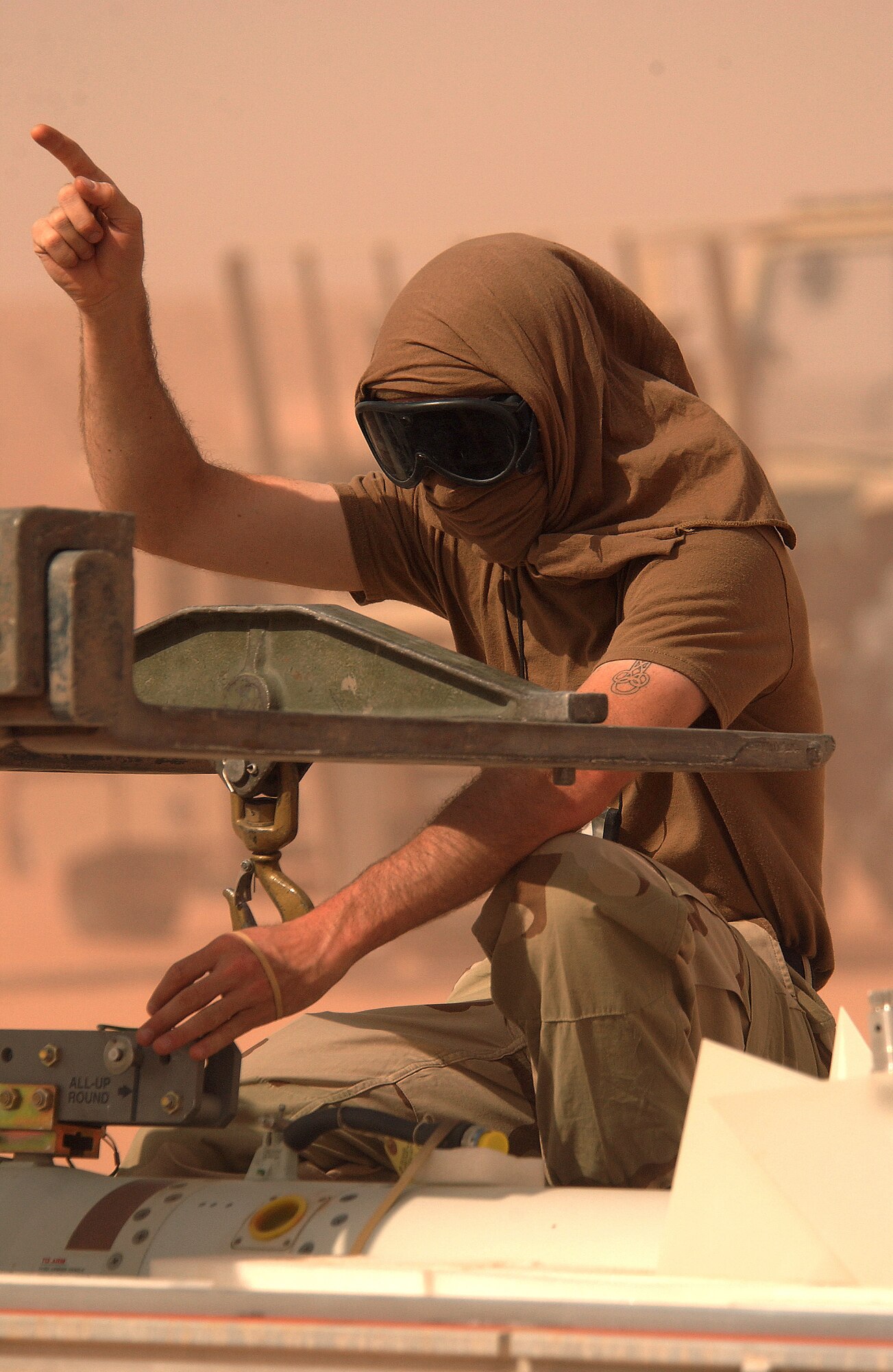 OPERATION IRAQI FREEDOM (AFPN) -- Staff Sgt. Jason Nipp protects his eyes during a sand storm while spotting a munitions handling unit carrying missile for an F-16 Fighting Falcon on the flightline at a forward-deployed location March 25.  Nipp is a crew chief with the 363rd Expeditionary Equipment Maintenance Squadron.  He is deployed from Ramstein Air Base, Germany.  Squadron members are working 12-hour days seven days a week.  (U.S. Air Force photo by Staff Sgt. Matthew Hannen) 