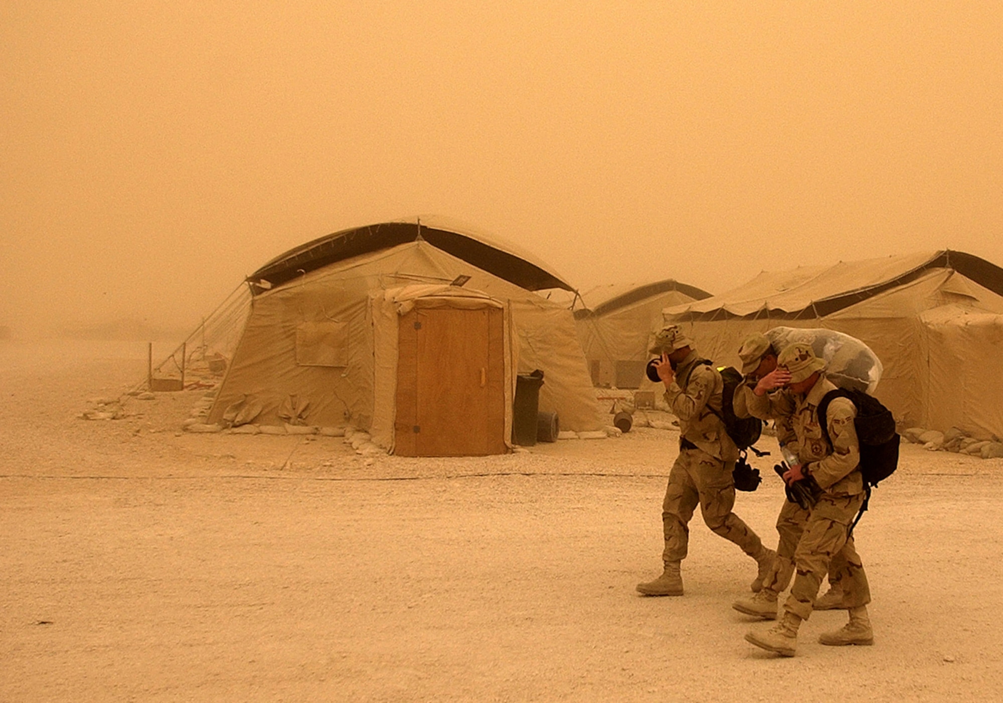 OPERATION IRAQI FREEDOM -- Airmen struggle to walk through a heavy sand storm at this forward-deployed air base March 26.  Troops supporting Operation Iraqi Freedom are battling sand storms throughout the Middle Eastern region.  (U.S. Air Force photo by Staff Sgt. Derrick C. Goode)                          