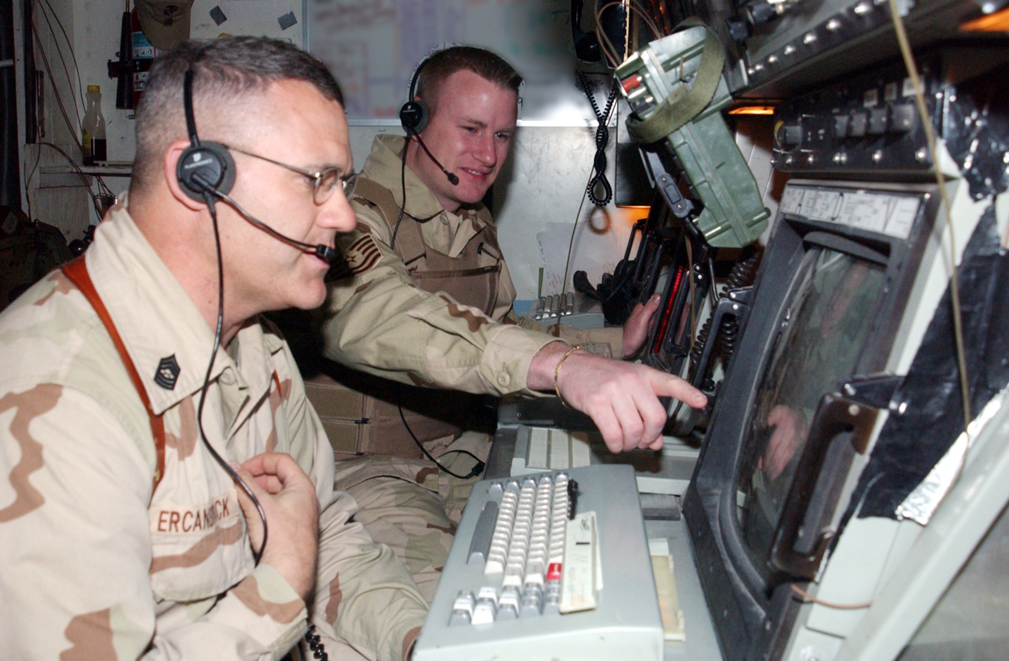 OPERATION IRAQI FREEDOM -- Tech. Sgt. Mark Morrison (background) consults with Marine Corps Master Sgt. Keith Ercanbrack at a control console.  Morrison is the only Air Force air traffic controller in the all-Marine crew that monitors aircraft returning to forward-deployed location.  He is with the 332nd Expeditionary Operations Support Squadron and deployed from the 46th Operations Support Squadron at Eglin Air Force Base, Fla. (U.S. Air Force Photo by Master Sgt. Stefan Alford)