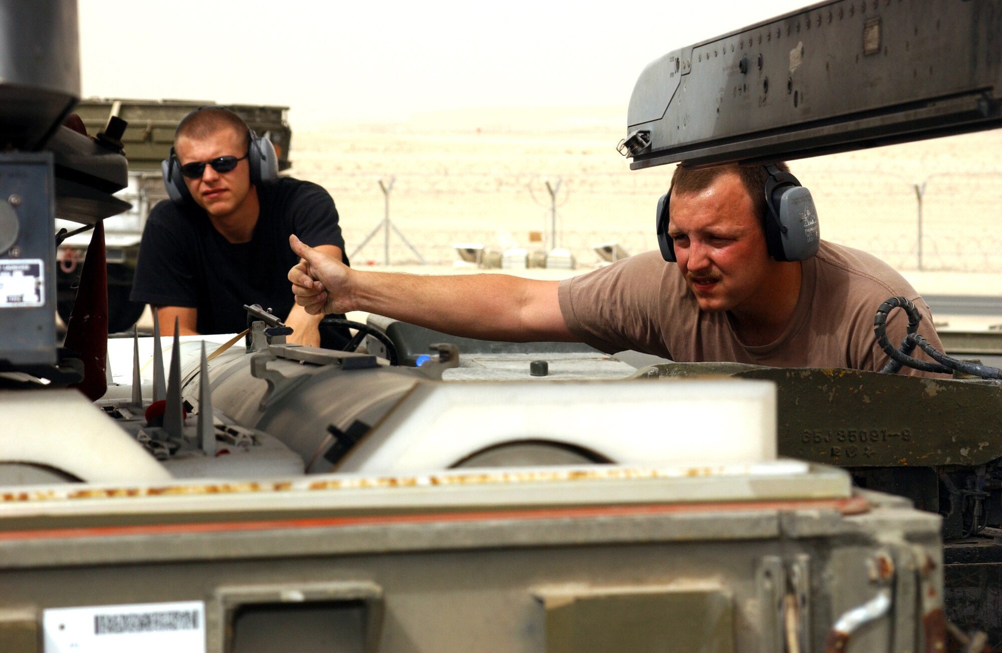 OPERATION IRAQI FREEDOM -- Airman 1st Class Michael Gucciardi drives the jammer while Staff Sgt. David Ross gives hand signals indicating which direction to move the missile while loading on a F-16CJ at a forward deployed location in Southwest Asia.(U.S. Air Force photo by Master Sgt. Terry L. Blevins)