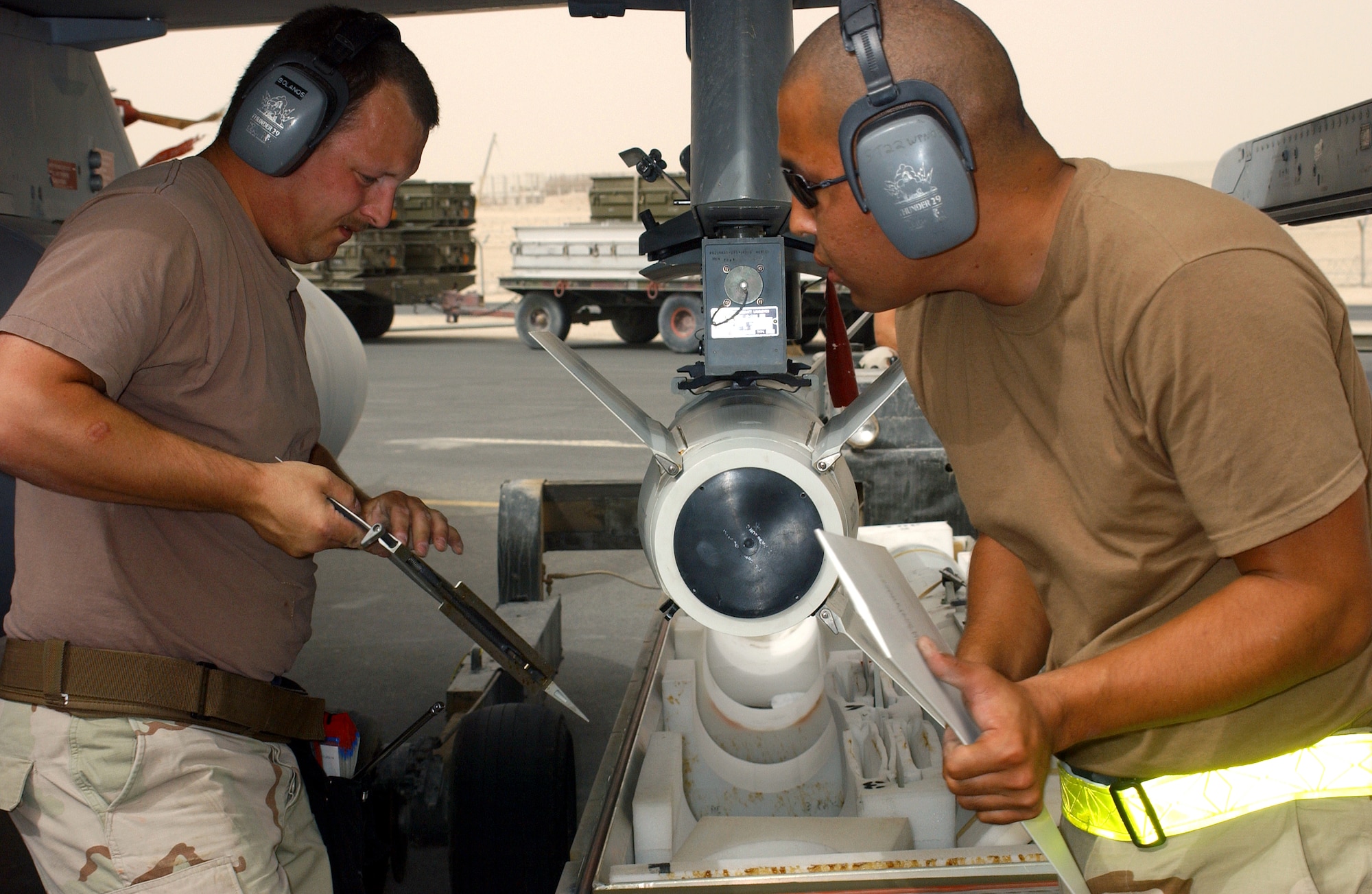 OPERATION IRAQI FREEDOM -- Staff Sgt. David Ross (left) and Airman 1st Class Eduardo Sera attach fins to a missile for an F-16 Fighting Falcon at a forward-deployed location in Southwest Asia.  (U.S. Air Force photo by Master Sgt. Terry L. Blevins)

