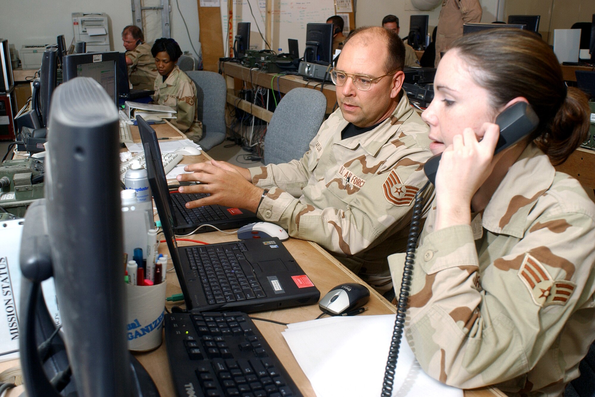 OPERATION IRAQI FREEDOM -- Tech. Sgt. Raymond Saylor and Senior Airman Kristina Degracia, Coalition Operations Center members, update sortie mission and flight filing.  Both are assigned to the 379 Air Expeditionary Wing at a deployed location. (U.S. Air Force by Master Sgt. Terry Blevins)