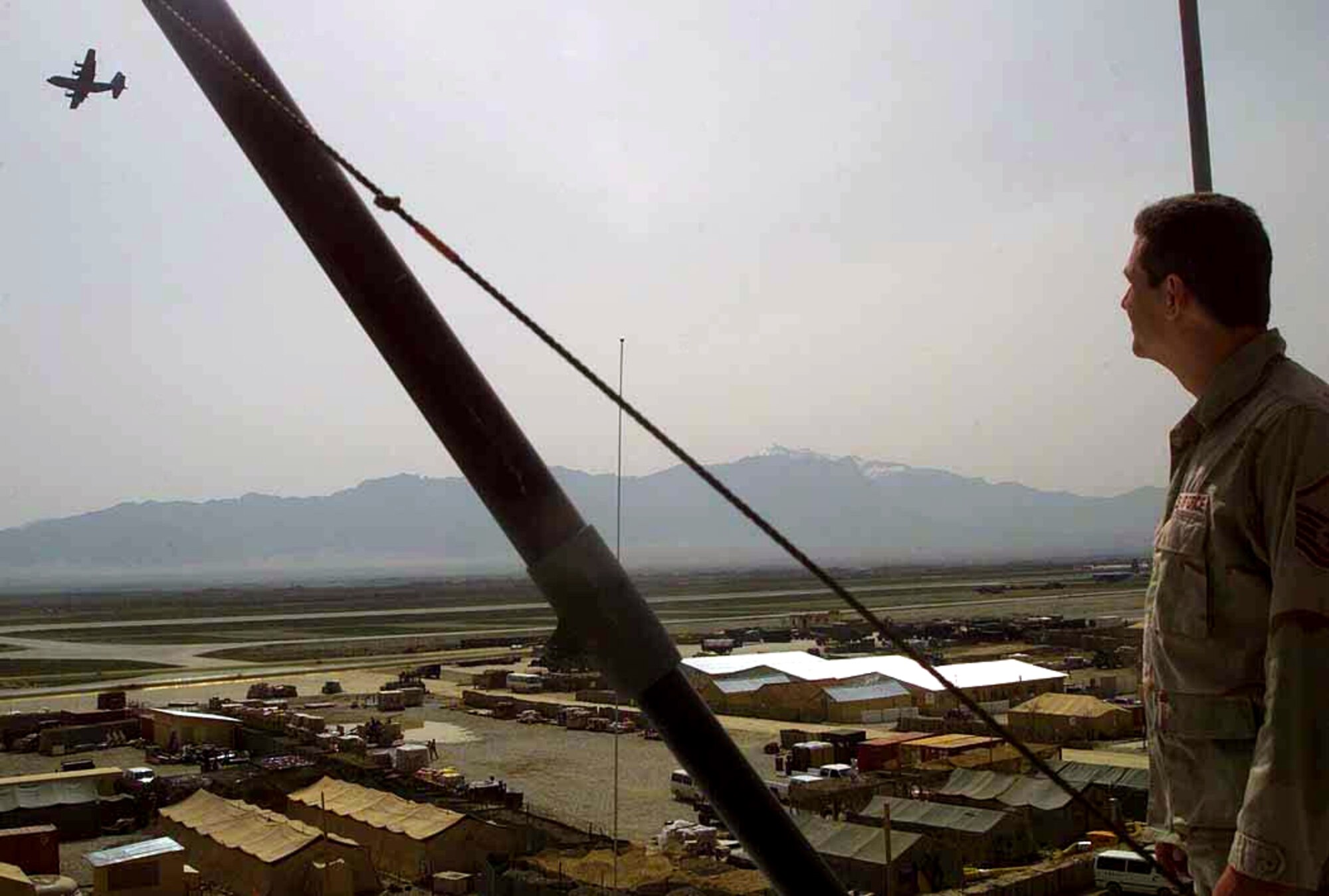 OPERATION ENDURING FREEDOM -- Master Sgt. Tim Sowder stands atop the flight tower watching as a C-130 Hercules takes off here March 26.  He is the chief controller at the tower and is assigned to the 455th Expeditionary Operations Group at Bagram, Afghanistan.  (U.S. Army photo by Pvt. Terri Rorke)