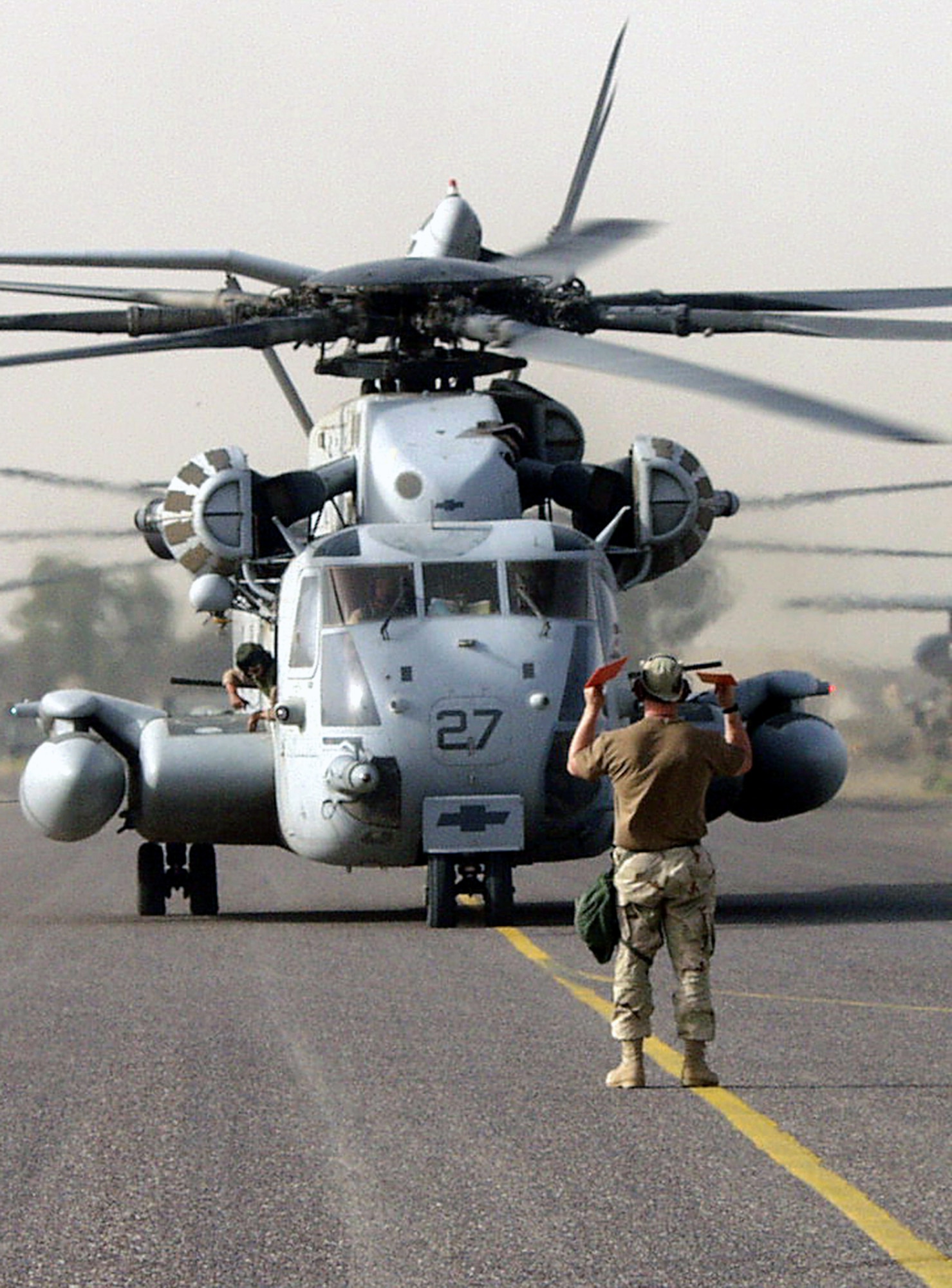 OPERATION IRAQI FREEDOM – Staff Sgt. Jassen Jack, directs a Marine CH-53 helicopter carrying Marines to a parking spot by a C-130. The 386th Transient Alert team played a key role in taking care of the aircraft transporting nearly 850 Marines moving forward to support operations in Iraq. Operation Iraqi Freedom is the multinational coalition effort to liberate the Iraqi people, eliminate Iraq’s weapons of mass destruction and end the regime of Saddam Hussein. (U.S. Air Force photo by Staff Sgt. Karen J. Tomasik)