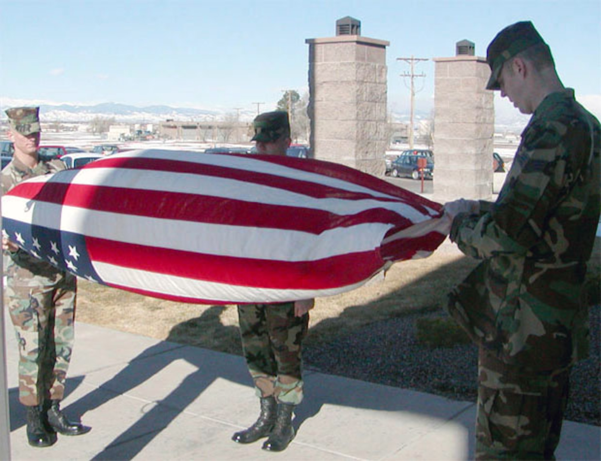 BUCKLEY AIR FORCE BASE, Colo. -- Marine Cpl. Kevin Ennet and Senior Airmen Michael Skaggs and John Stacy fold an American flag after flying it on the flagpole here. In 1968, the flag was lowered on Mount Suribachi on the island of Iwo Jima for the last time as the island returned to the Japanese government. (U.S. Air Force photo by Master Sgt. Jim Randall)