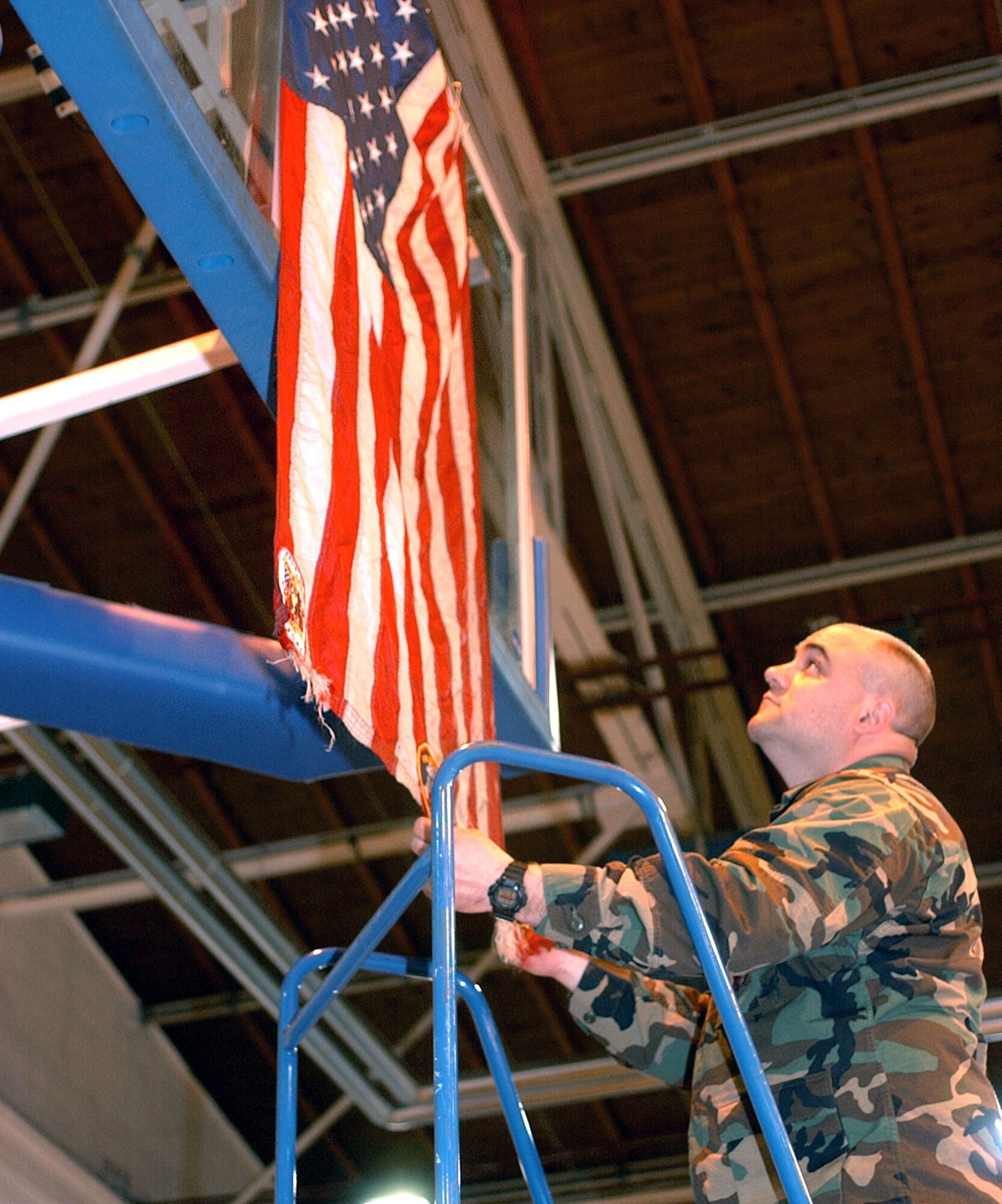 RAMSTEIN AIR BASE, Germany -- Capt. Eric Szillus, a clinical nurse with the 514th Aeromedical Staging Squadron from McGuire AFB, hangs an American flag flown at Ground Zero in the Ramstein Southside Fitness Center.  (U.S. Air Force photo by Airman 1st Class Melissa Maraj)                