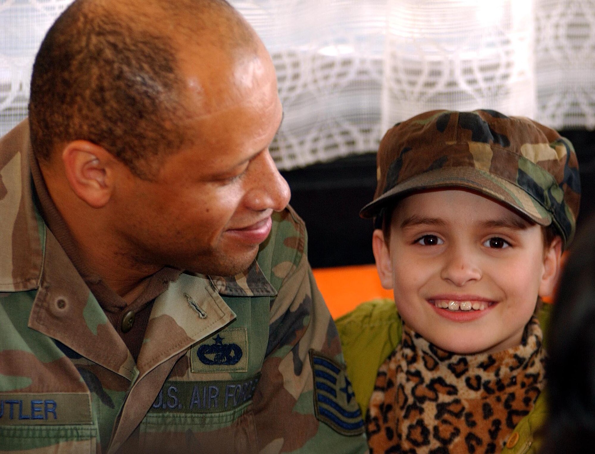 OPERATION IRAQI FREEDOM -- Tech. Sgt. Terrance Butler shares his hat with a Bulgarian child April 2. Butler is currently assigned to the 409th Air Expeditionary Group at Camp Sarafovo, Bulgaria. More than 40 children from two orphanages in nearby Burgas toured the camp and entertained the deployed troops. (U.S. Air Force photo by Master Sgt. Dave Ahlschwede) 
