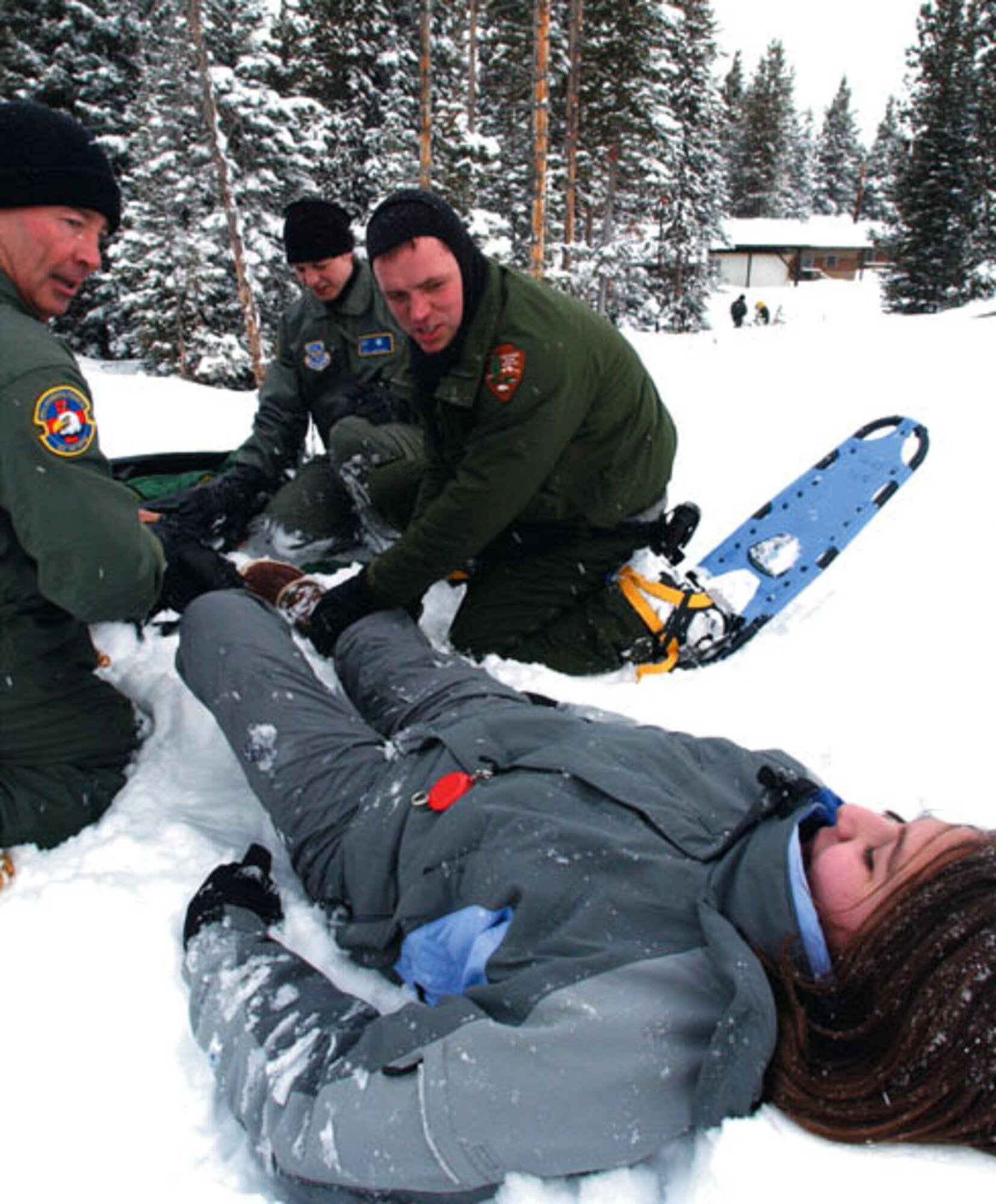 YELLOWSTONE NATIONAL PARK -- Senior Master Sgt. Johnny Cupp (left) and 1st Lt. Stacy Gartrell, officer in charge of the 445th Aeromedical Staging Squadron's National Park Service/EMT training program, assess a "patient's" injury with the help of park ranger Tim Townsend.  The airmen are here as part of a medical exercise called Winterops 2003.  (U.S. Air Force photo by Bo Joyner)