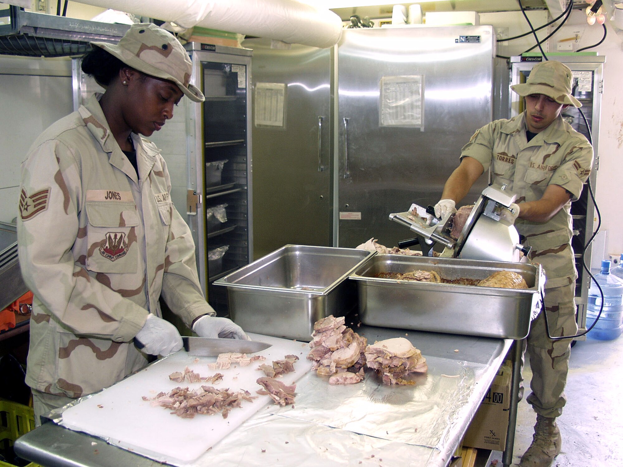 OPERATION IRAQI FREEDOM –- Staff Sgt. Phyllis Jones and Airman 1st Class Hari Torres prepare turkey ala king for a Camp Chariot dinner meal. The services squadron food services flight supported a base surge of 590 percent in January. Sixty-three service members worked in food service before hostilities started and that number has risen to 83 members currently working in food services. Operation Iraqi Freedom is the multinational coalition effort to liberate the Iraqi people, eliminate Iraq’s weapons of mass destruction and end the regime of Saddam Hussein. (U.S.  Air Force photo)