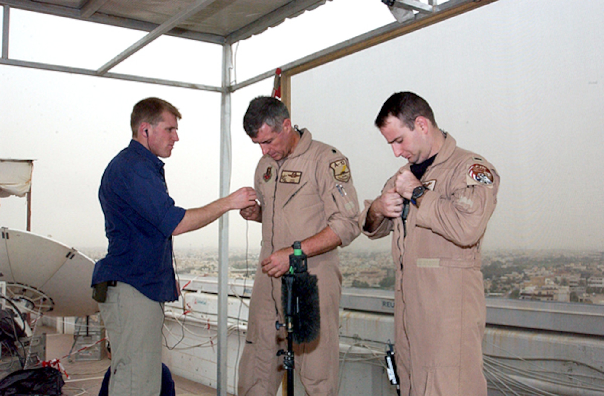 OPERATION IRAQI FREEDOM -- A sound technician assists Lt. Col. Mike Webb and 1st Lt. Chad Martin, 332nd Air Expeditionary Wing fighter pilots, with their microphones prior to a live satellite feed from Kuwait City. (U.S. Air Force Photo by Master Sgt. Stefan Alford)