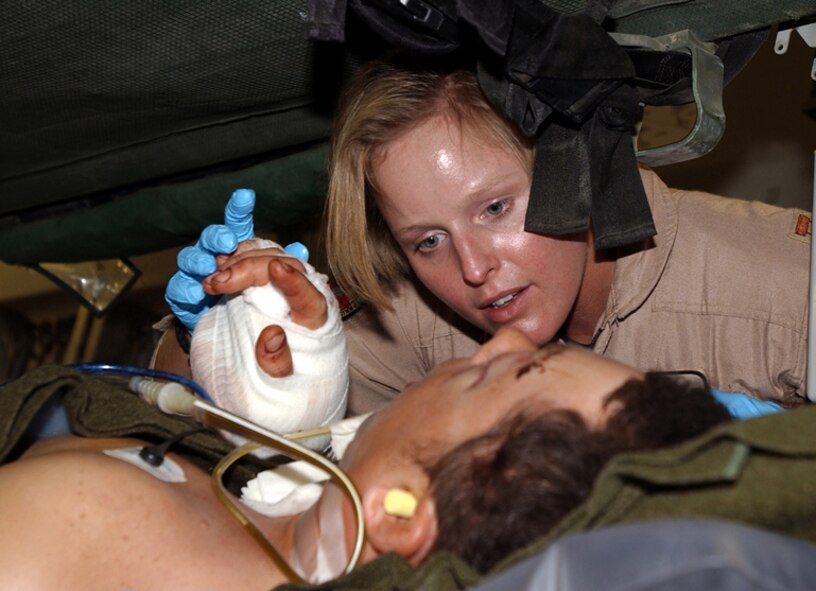 FILE PHOTO (AFPN) -- Capt. Kristen McCabe holds a soldier's hand and talks to him during his flight to Germany.  The special-forces soldier was seriously injured in an ambush in southern Afghanistan recently.  McCabe is a Critical Care Aeromedical Transport Team nurse with the 438th Expeditionary Aeromedical Evacuation Squadron supporting Operation Enduring Freedom.  (U.S. Army photo by Cpl. Keith Kluwe)