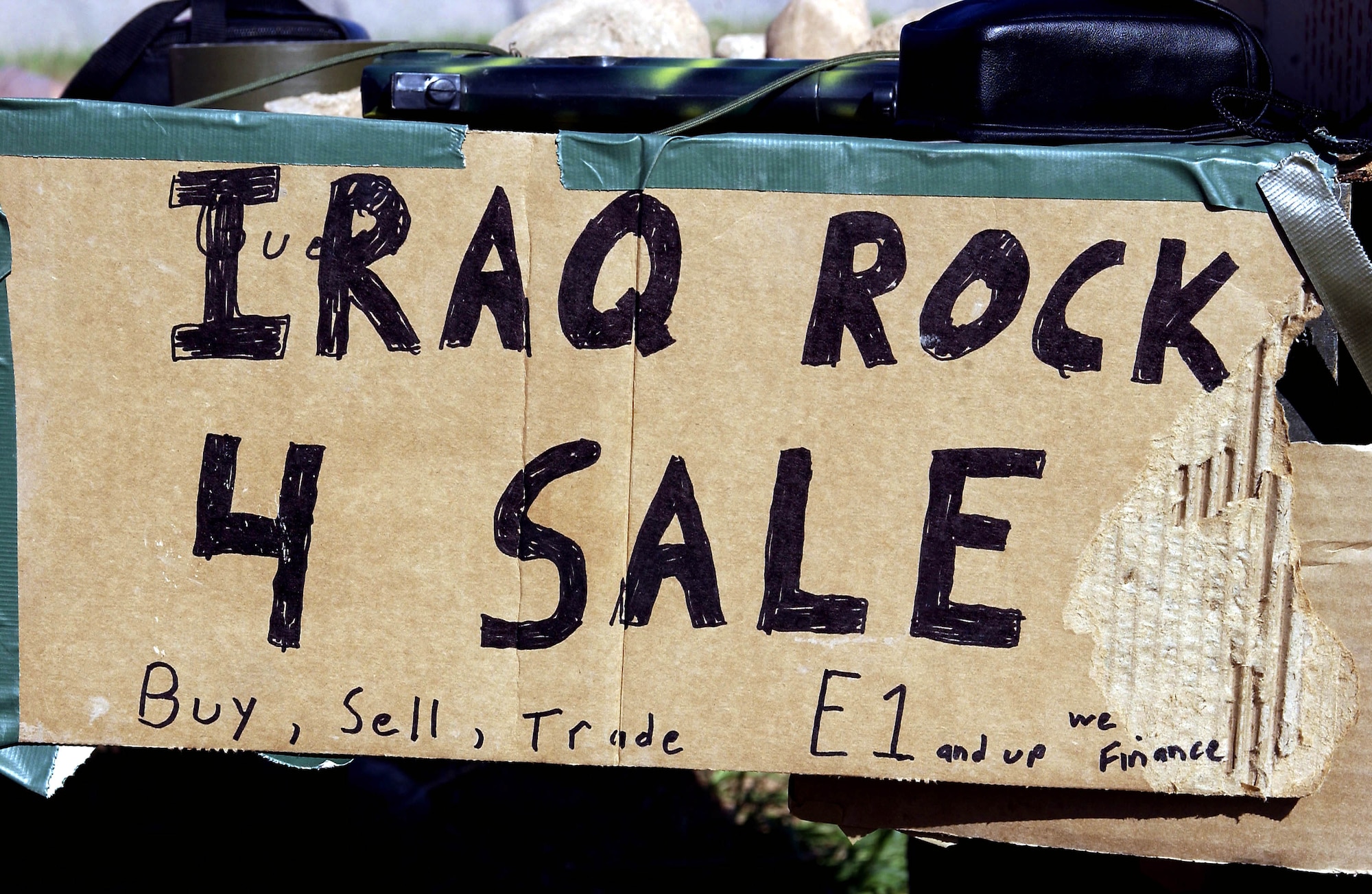 OPERATION IRAQI FREEDOM -- The rock merchants' sign to passing aircrews at Bashur Airfield in northern Iraq tells it all.  Three airmen from the 86th Expeditionary Contingency Response Group at Ramstein Air Base, Germany, are selling rocks to passing aircrews as a way to let off steam from their jobs on the flightline.  (U.S. Air Force photo by Master Sgt. Keith Reed)