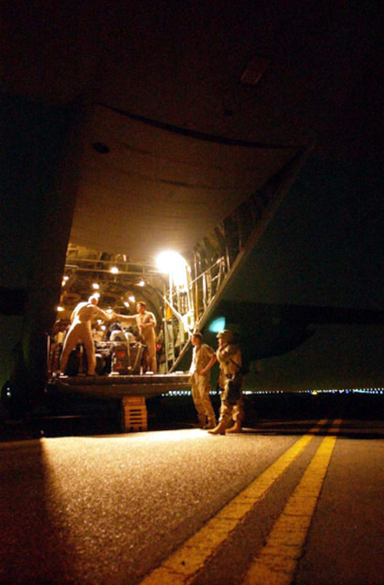 OPERATION IRAQI FREEDOM -- U.S. Air Force personnel secure humanitarian pallets onto a C-130 Hercules that will be flown to Baghdad to help Iraqi citizens in need. The flight marked the first of flights delivering supplies that are being donated from the people of Kuwait as part of a coordinated effort with the U.S. military to transport and deliver aid to the people of Iraq in support of Operation Iraqi Freedom. (U.S. Navy photo by PH1(SW) Arlo Abrahamson)