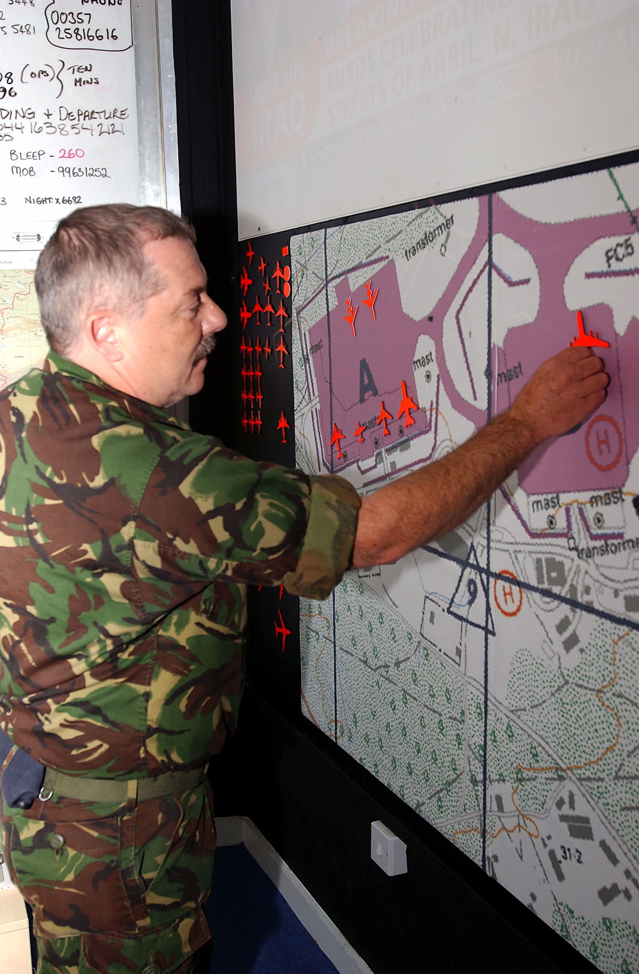 OPERATION IRAQI FREEDOM -- Royal Air Force Sgt. Dave Brumby, movement controller, arranges aircraft silhouettes on a map of the airfield parking plan.  401st Air Expeditionary Wing command post personnel are working side-by-side with their British counterparts supporting Operation Iraqi Freedom.  (U.S. Air Force photo by Airman 1st Class Melisa Kelly).   