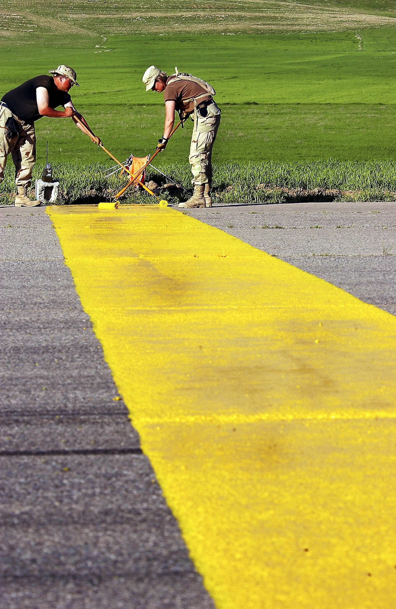 OPERATION IRAQI FREEDOM -- Staff Sgt. Eric John Wood (left), a crew chief, and Tech. Sgt. Christina Bolle, an airfield management troop, paint the end-of-runway stripe at Bashur Airfield, Iraq.  The heavy wear on the runway caused cracks, which forced the 86th Expeditionary Contingency Response Group, which operates the airfield, to shorten the runway by about 2,000 feet.  (U.S. Air Force photo by Master Sgt. Keith Reed)