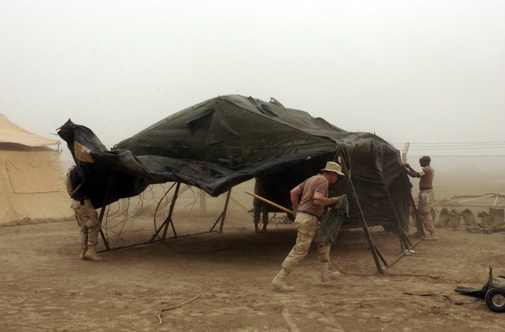 OPERATION IRAQI FREEDOM - Airmen from the 5th Combat Communications Group pitch in to set up a tent during a sandstorm at Tallil Air Base in southern Iraq on April 16.  The 5th CCG deployed from Robins Air Force Base, Ga., to Tallil recently.  (U.S. Air Force photo by Master Sgt. Terry L. Blevins)