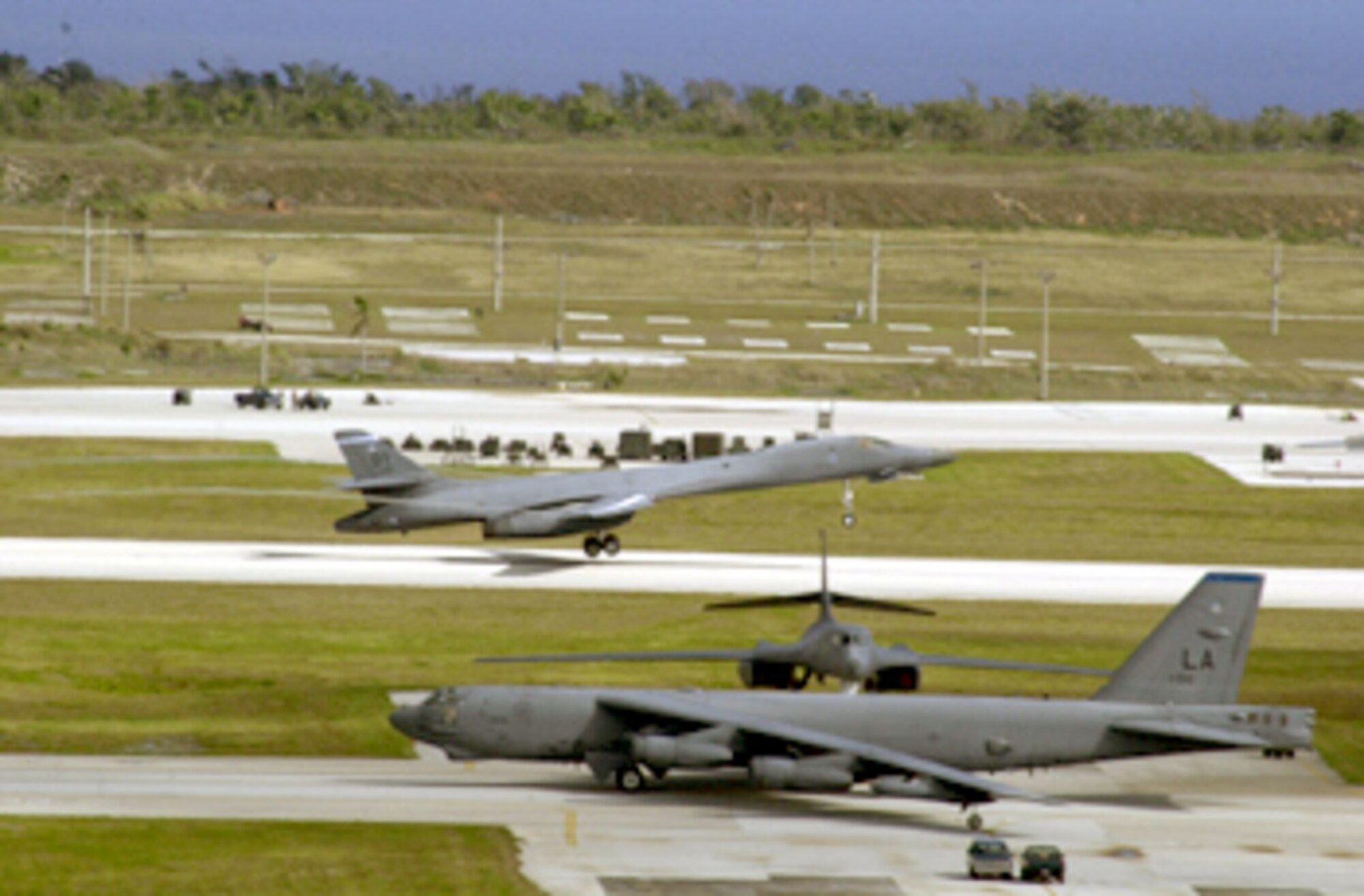 ANDERSEN AIR FORCE BASE, Guam -- A B-1B Lancer takes off as a B-52 Stratofortress taxies past, readying for take-off here during last day of surges April 2.  (U.S. Air Force photo by Staff Sgt. Charlene M. Franken)
