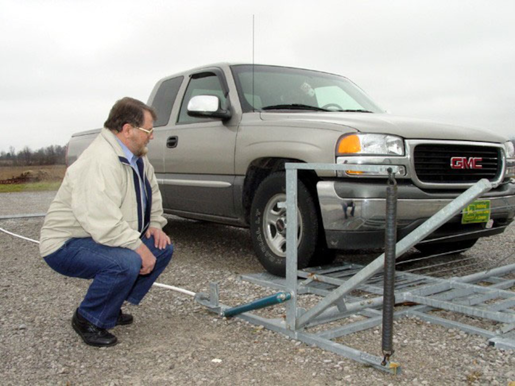 ARNOLD AIR FORCE BASE, Tenn. -- Dan Hix watches as friend Ernest Finney demonstrates the automatic cattle gate Hix invented.  Hix is software analyst with the Arnold Engineering Development Center here.  He has a patent for a self-opening gate that operates with no electricity, batteries, solar panels or remote controls.  (U.S. Air Force photo by Danette Duncan)