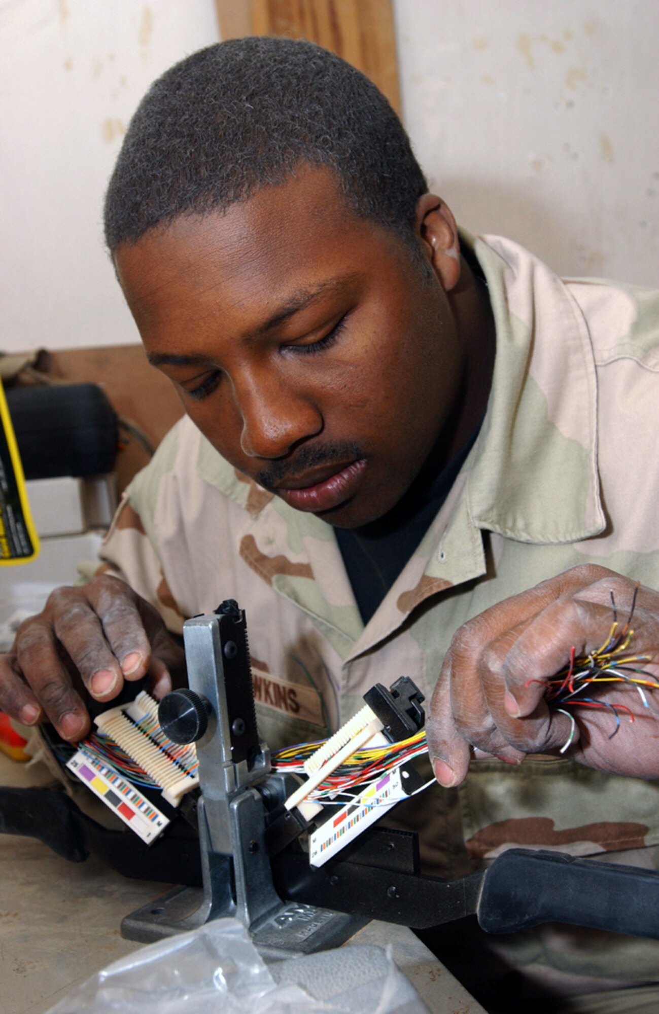 OPERATION IRAQI FREEDOM -- Staff Sgt. Kelvin Hawkins makes a connection on a communications cable at Tallil Air Base in southern Iraq.  Hawkins is a telephone systems technician with the 5th Combat Communications Group from Robins Air Force Base, Ga.  (U.S. Air Force photo by Master Sgt. Terry L. Blevins)