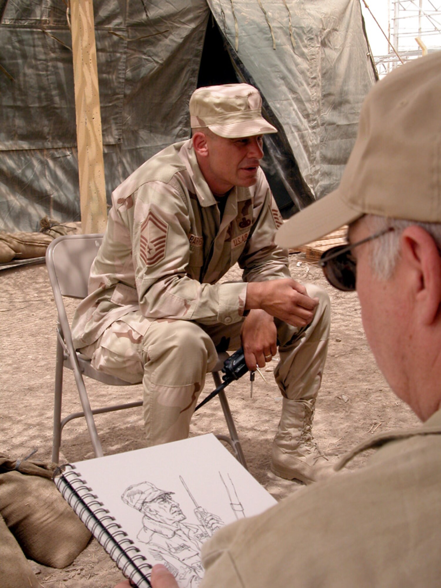 OPERATION IRAQI FREEDOM (AFPN) -- Aviation artist John Witt sketches Senior Master Sgt. Keith D. Barkema, a fuels superintendent for the 407th Air Expeditionary Group at Tallil Air Base in southern Iraq.  Witt was one of four artists visiting the austere, frontline air base on behalf of the Air Force Art Program.  The program allows artists to document and capture Air Force operations in war and peacetime.  (U.S. Air Force photo by Bob Jensen)