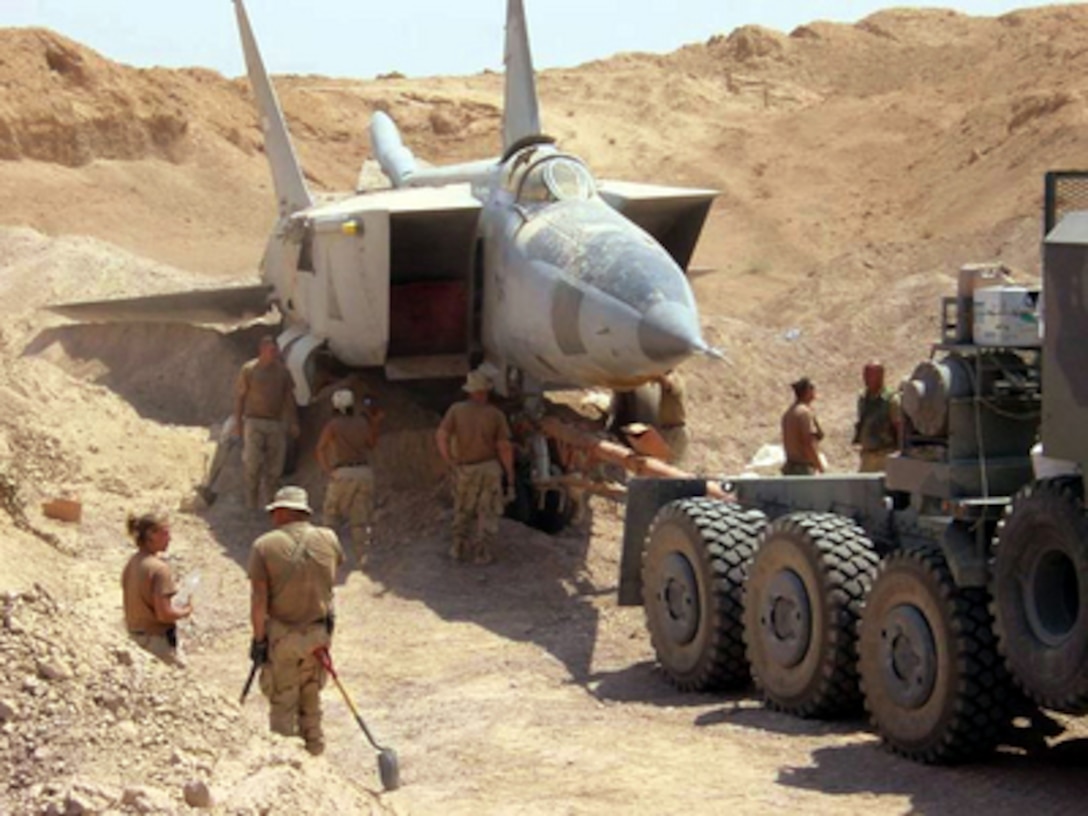 U.S. forces use heavy equipment to pull a MiG-25R Foxbat-B from beneath the sands in Iraq on July 6, 2003. A U.S. military search team has uncovered several MiG-25s and Su-25 ground attack jets found buried at Al-Taqqadum airfield west of Baghdad. 