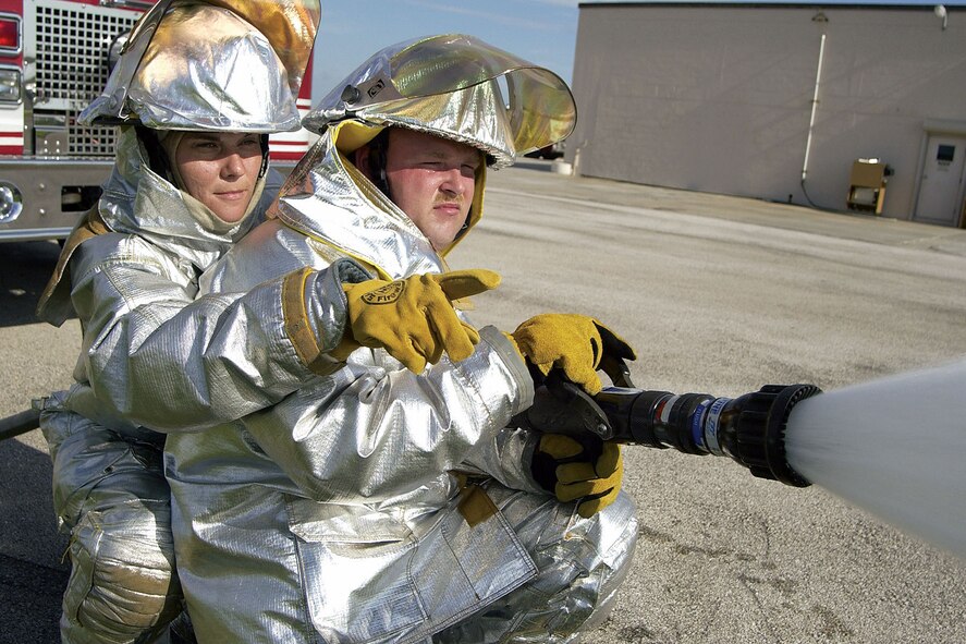 PATRICK AIR FORCE BASE, Fla. -- Staff Sgt. Suzanne Blundell (left), a 45th Civil Engineer Squadron firefighter, directs Senior Airman Jamey Eaton during fire hose training.  Blundell is the only female firefighter at the base fire station.  (U.S. Air Force photo by Jim Laviska)